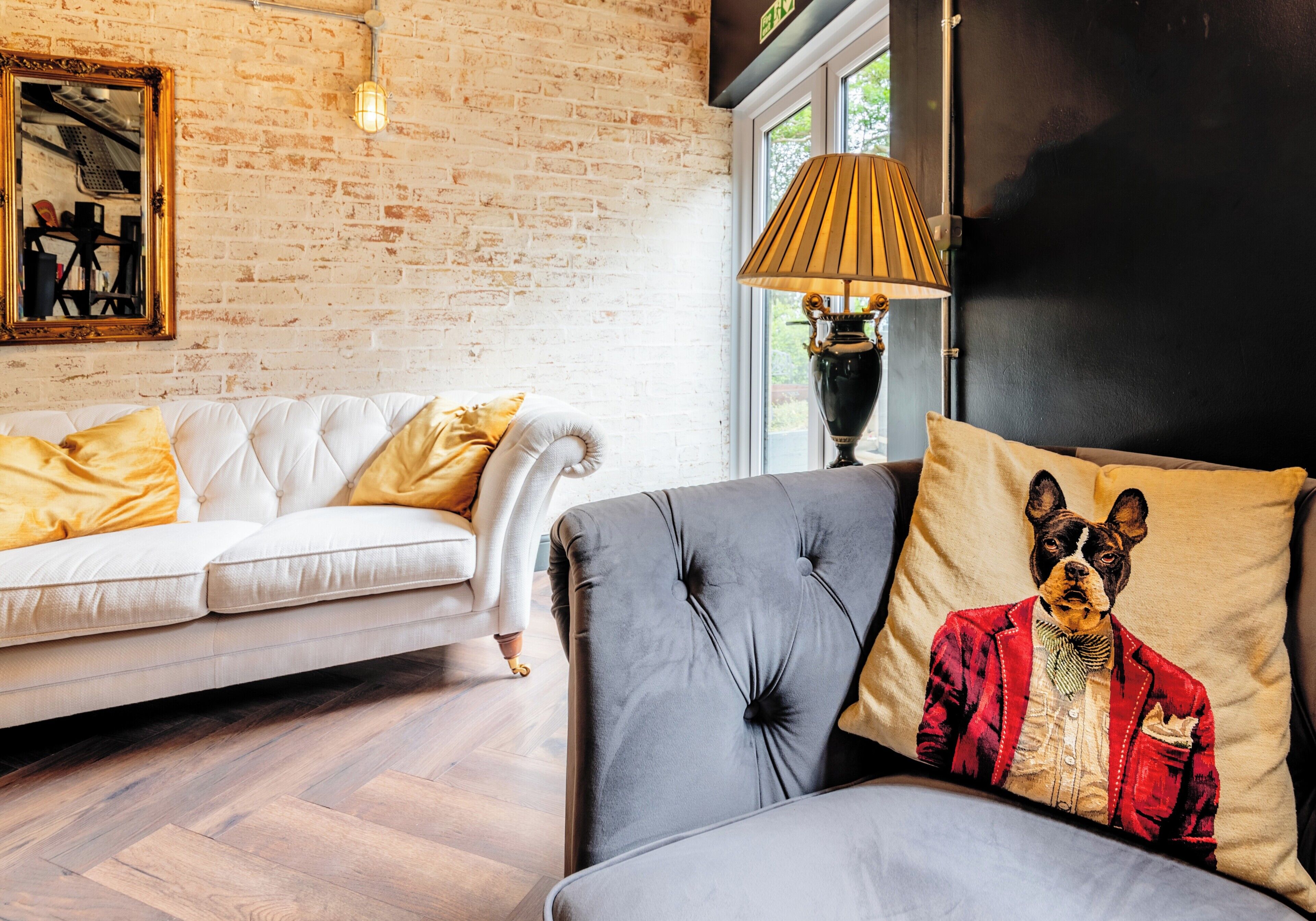A modern living room with a white sofa, a grey sofa with a decorative pillow, and a lamp.