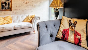 A modern living room with a white sofa, a grey sofa with a decorative pillow, and a lamp.