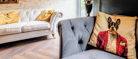 A modern living room with a white sofa, a grey sofa with a decorative pillow, and a lamp.