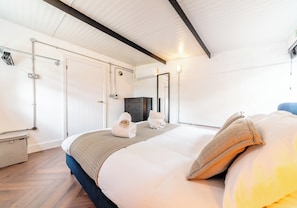 A hotel room with a bed, a wardrobe, a mirror, and a small desk.