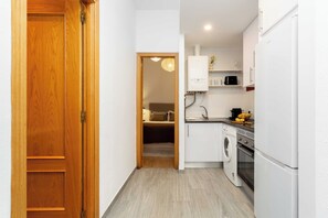 A compact kitchen with a washing machine, a microwave, and a refrigerator. - A one-bedroom in the heart of Chueca, where jewel-box interiors create a quiet world of their own amid Madrid's best galleries, restaurants and nightlife. (MADRID)