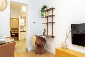 A modern living room with a dining area, a TV mounted on the wall, and a built-in shelf with decorative items. - A one-bedroom in the heart of Chueca, where jewel-box interiors create a quiet world of their own amid Madrid's best galleries, restaurants and nightlife. (MADRID)