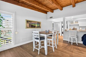 A modern kitchen with white cabinets and a wooden ceiling.