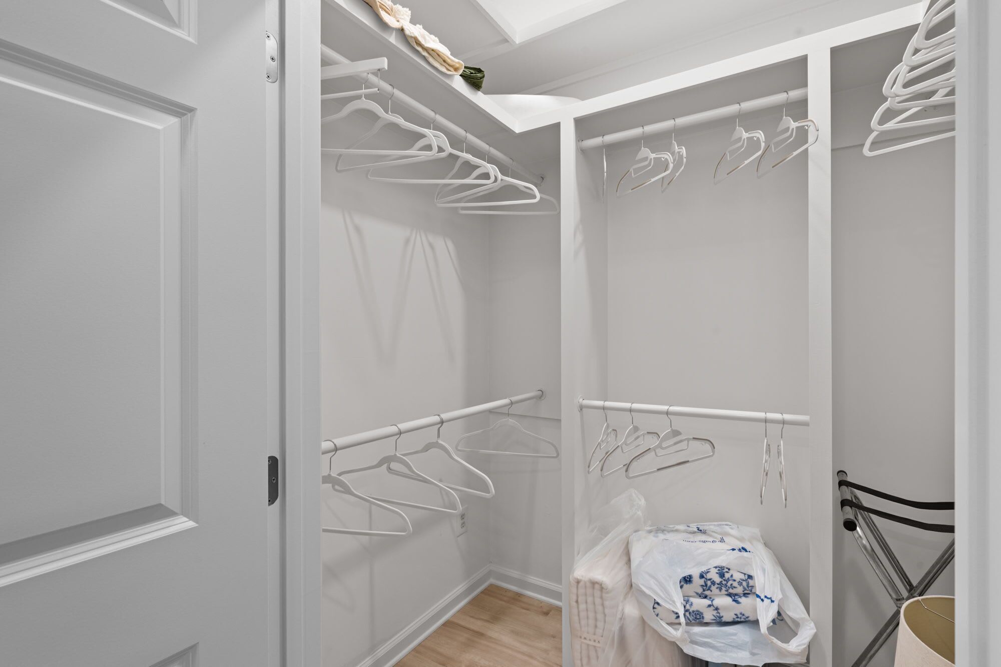 Um closet amplo com cabides brancos e uma toalha branca em um suporte.