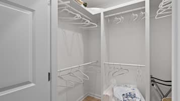 Um closet amplo com cabides brancos e uma toalha branca em um suporte.