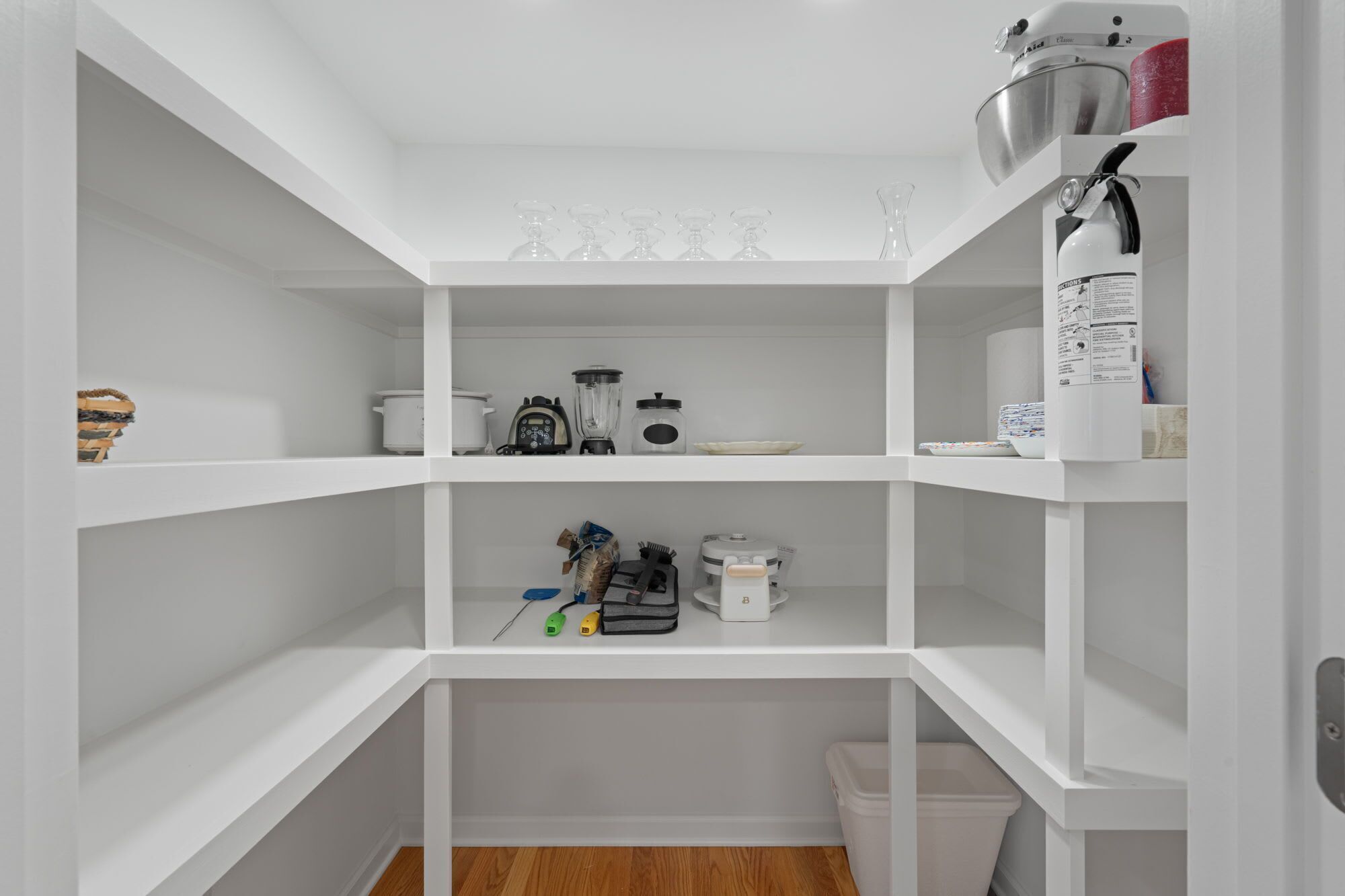 A white interior with a kitchen area, including a stove, blender, and various kitchen utensils.