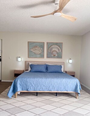 A bedroom with a bed, a ceiling fan, two wall-mounted lamps, and two framed pictures on the wall. - Boho Coastal Studio • Near Siesta Key • Pool (Sarasota)