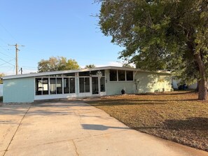 A single-story building with a garage, a covered porch, and a small front yard.