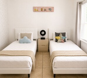 Une chambre avec deux lits, une œuvre d’art accrochée au mur et une table de chevet agrémentée d’un objet décoratif.