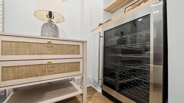 A kitchen with a built-in oven, a wooden cabinet with a woven front panel, and a hanging lamp.