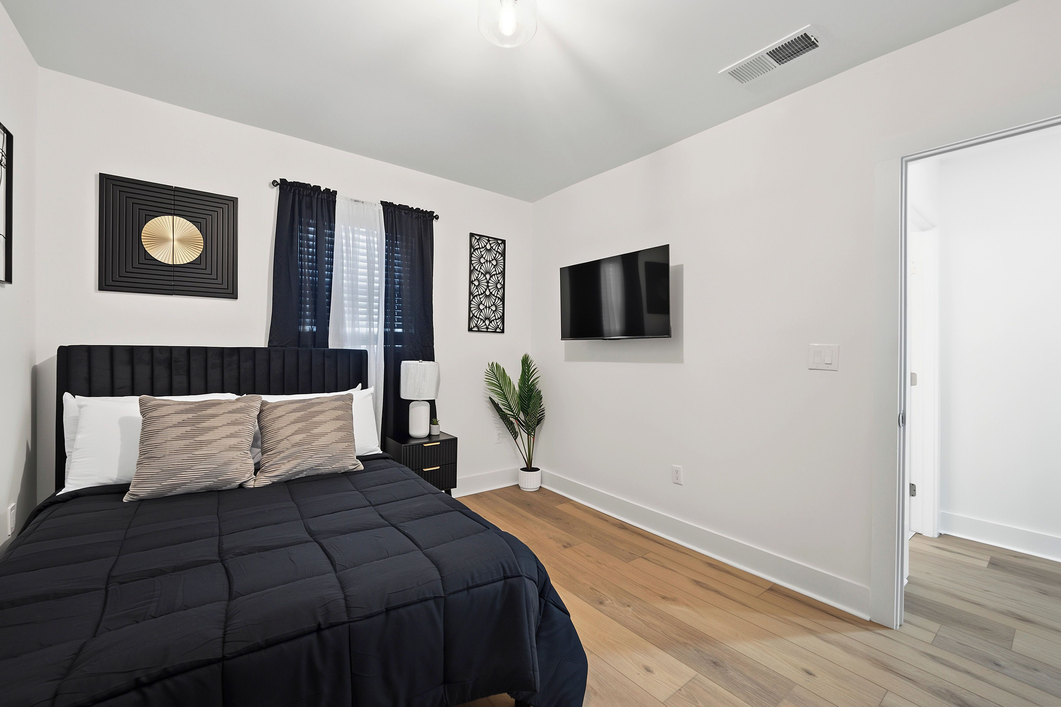 Un dormitorio con una cama, un televisor y una planta.