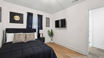 Une chambre à coucher avec un lit, une télévision et une plante.