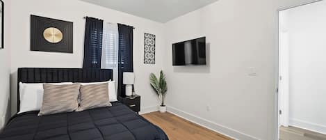 A bedroom with a bed, a TV, and a plant.
