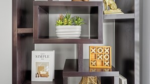 A dark wooden shelving unit with various items including a potted plant, a framed picture, and decorative objects.
