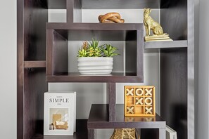 A dark wooden shelving unit with various items including a potted plant, a framed picture, and decorative objects.