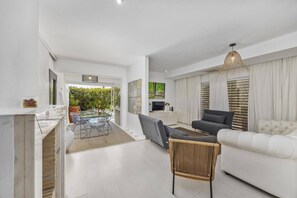 A modern living room with a white sofa, a glass dining table, and clear chairs. - Villa Casa Rafael by Villa Plus (Albufeira)