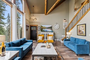 A spacious living area with a large window, a fireplace, a dining table with chairs, and a staircase. - Scenic and Spacious 4 Bedroom, 3.5 Bath Just Outside of Breckenridge (Blue River)