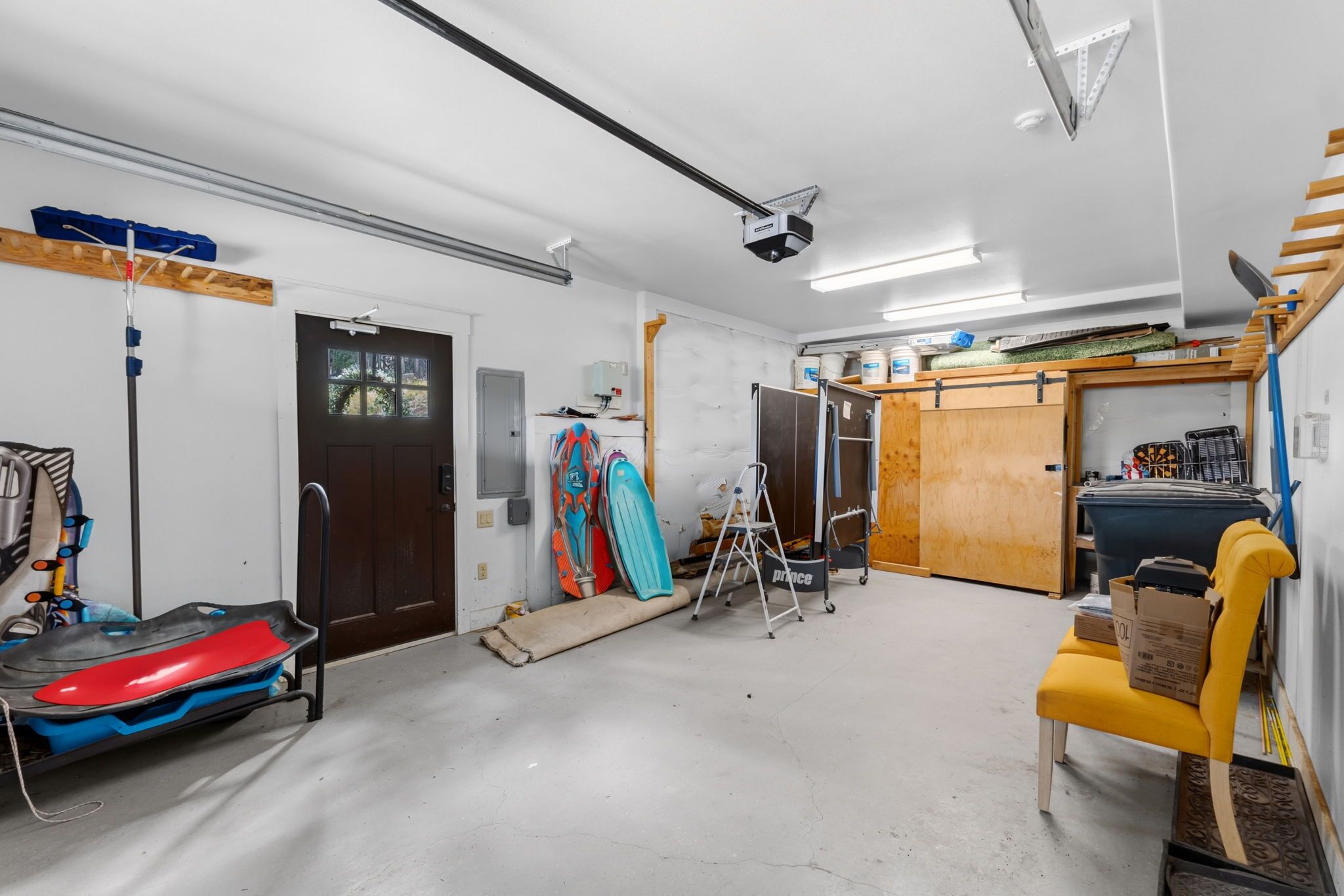 A garage with a workbench, a kayak, and a yellow chair.