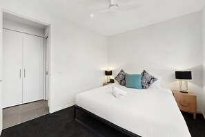 Ein Hotelzimmer mit einem Bett, zwei Nachttischen, einer Stehlampe und einer Deckenventilator.