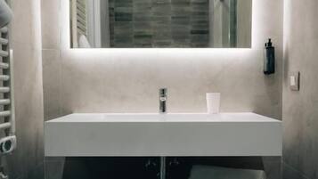 Un bagno moderno con lavabo integrato, uno specchio e un portasciugamani.