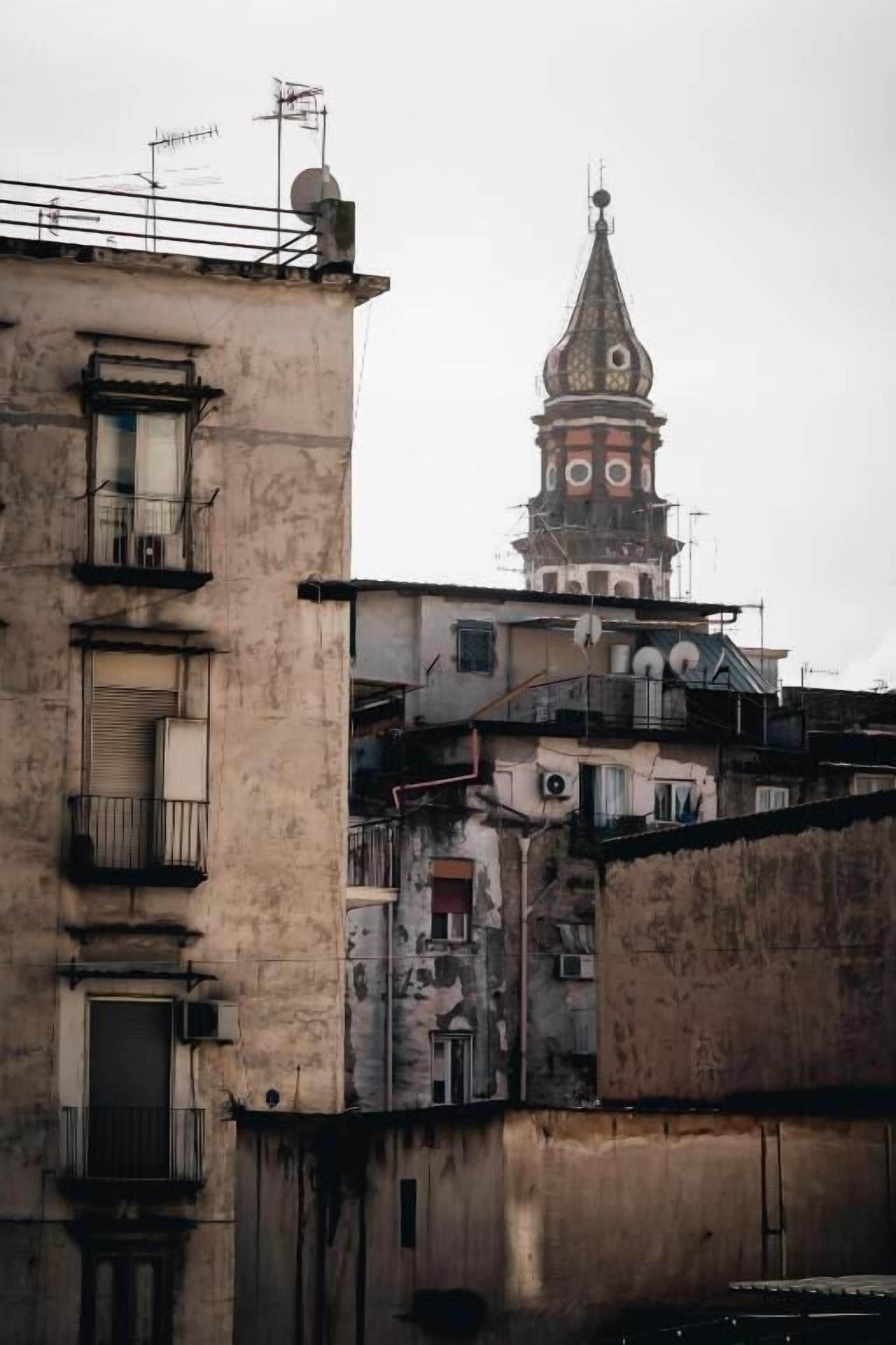 A building with a tower, balconies, and a weathered facade.