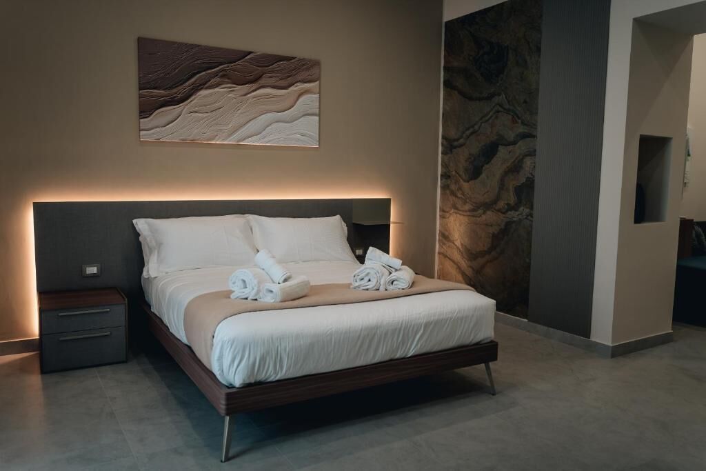 Un dormitorio moderno con una cama, una mesita de noche y una obra de arte colgada en la pared.