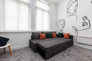 A modern living room with a grey sectional sofa, a white radiator, and a window with blinds. - Near Cavern Club 2-storey Westminster (Liverpool)