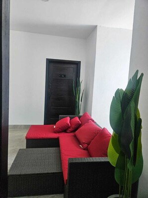 A room with a dark door, a red sofa with cushions, and a large green plant. - Coastal Villa ,Stunning Sea Views in Portland (Saint Margarets Bay)