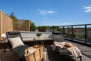 A rooftop terrace with two lounge chairs, a small table with drinks, and a view of the city. - Apartment with a roof terrace - Seaside (Gdańsk)