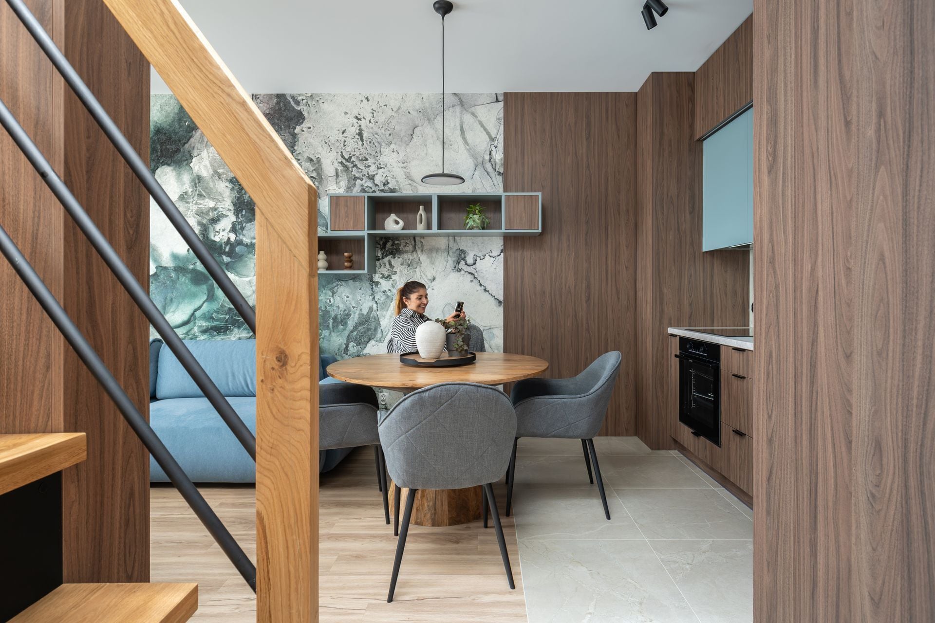 Eine moderne Küche mit Essbereich, Holzelementen und einer Marmor-Spritzschutzwand.
