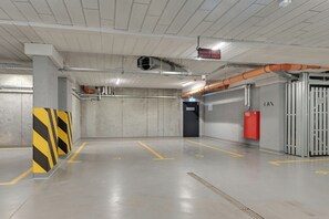 A clean, empty parking garage with concrete walls, a yellow and black striped barrier, and a red fire extinguisher. - Apartment with a roof terrace - Seaside (Gdańsk)