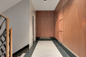 A modern hallway with a wooden panel wall, a marble floor, and a metal staircase. - Apartment with a roof terrace - Seaside (Gdańsk)