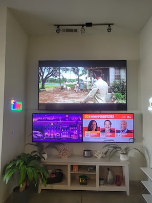 A television mounted on a wall with multiple screens displaying different content. - Delightful 2-bedroom apartment with AC in vibrant Downtown Dallas entertainment (Dallas)