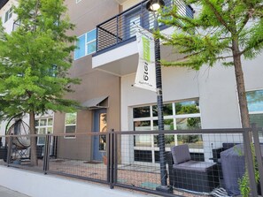 Un bâtiment moderne doté d’un balcon, d’un espace extérieur aménagé et d’une enseigne.