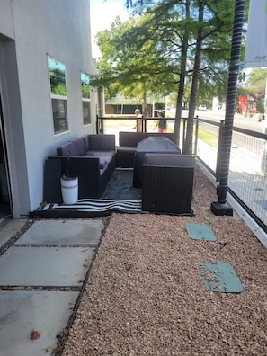 An outdoor seating area with a sofa, a small table, and a trash bin. - Delightful 2-bedroom apartment with AC in vibrant Downtown Dallas entertainment (Dallas)