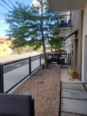 A patio area with a seating arrangement, a tree, and a view of the street. - Delightful 2-bedroom apartment with AC in vibrant Downtown Dallas entertainment (Dallas)