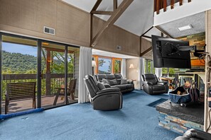 A spacious living area with a large TV, comfortable seating, and a fireplace.