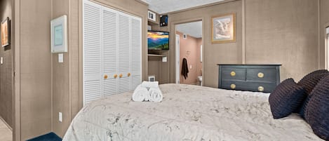 Une chambre à coucher avec un lit, une armoire, un téléviseur et un ventilateur de plafond.