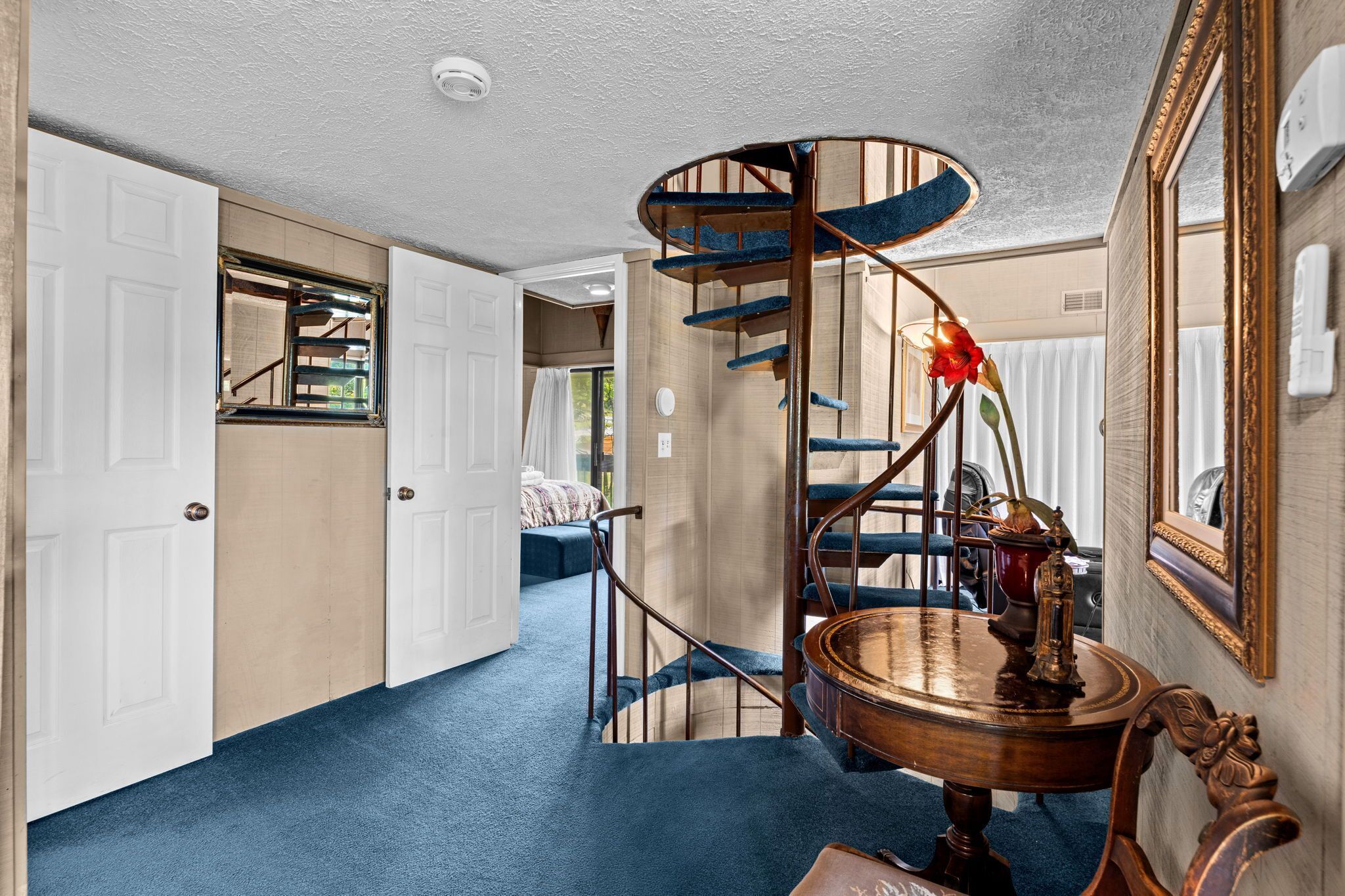 Eine Wendeltreppe mit blauen Stufen und einem Holztisch mit einer Messinglampe.