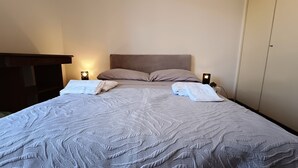 A neatly made bed with pillows and folded towels, two bedside lamps, and a wardrobe in a hotel room. - Private Room at the Villa nel Verde Residence in Rome-Ciampino (roma)