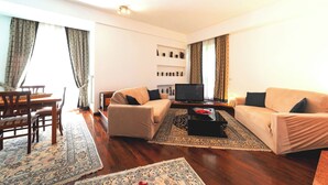 A living room with a sofa set, a television, a coffee table, and a dining area with chairs and a table. - Private Room at the Villa nel Verde Residence in Rome-Ciampino (roma)