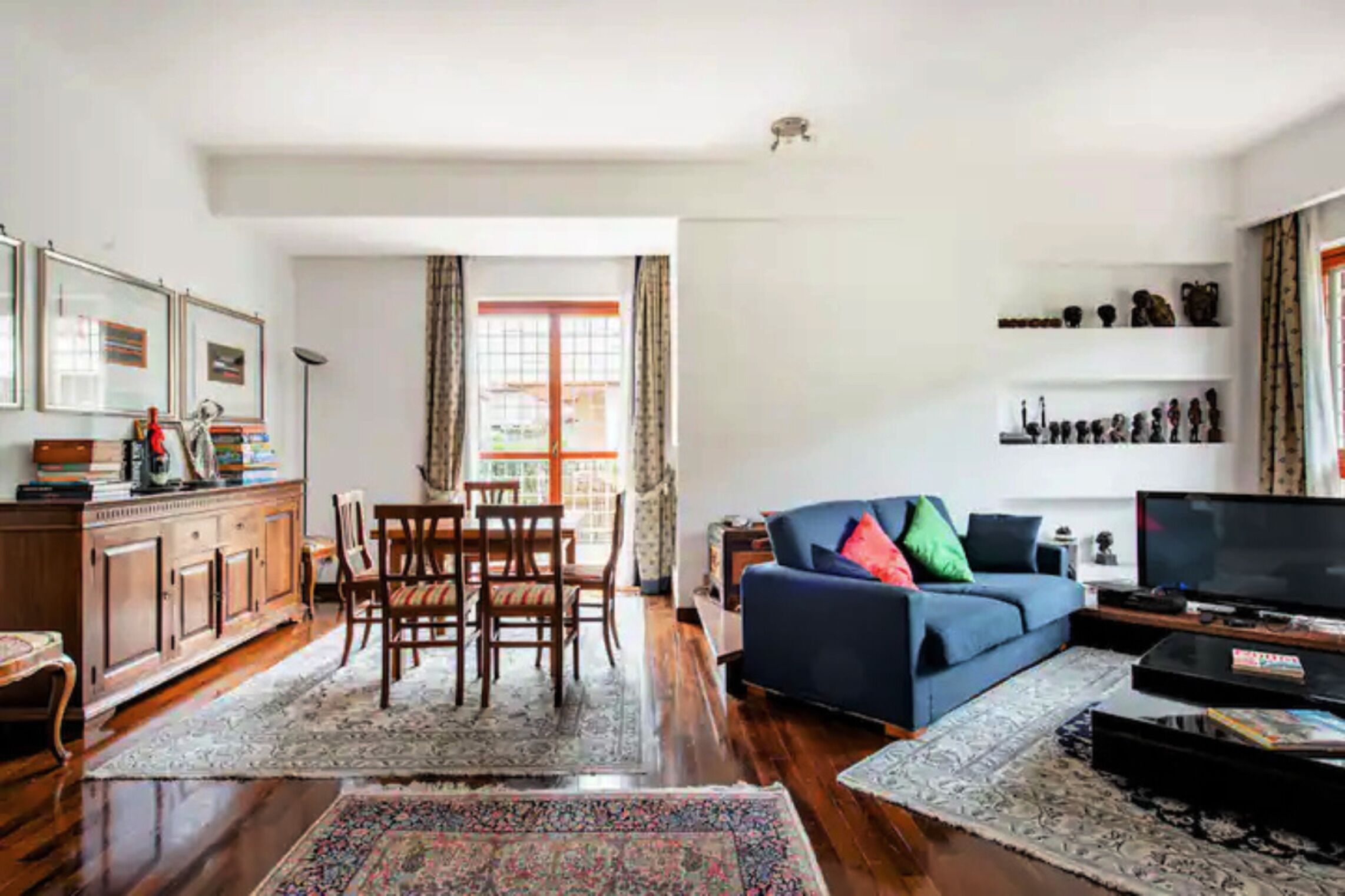 A living room with a sofa, television, and a dining area with chairs and a table.