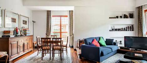 A living room with a sofa, television, and a dining area with chairs and a table.