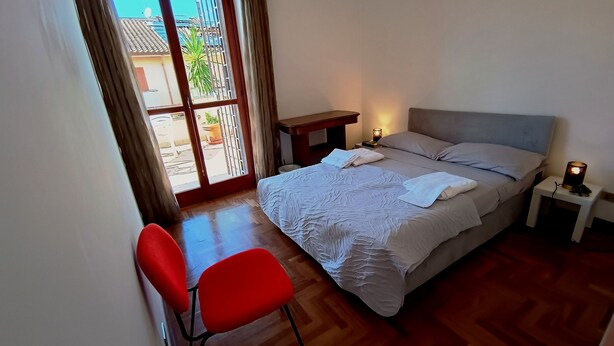 A bedroom with a bed, bedside tables, a chair, and a view through a window. - Private Room at the Villa nel Verde Residence in Rome-Ciampino (roma)