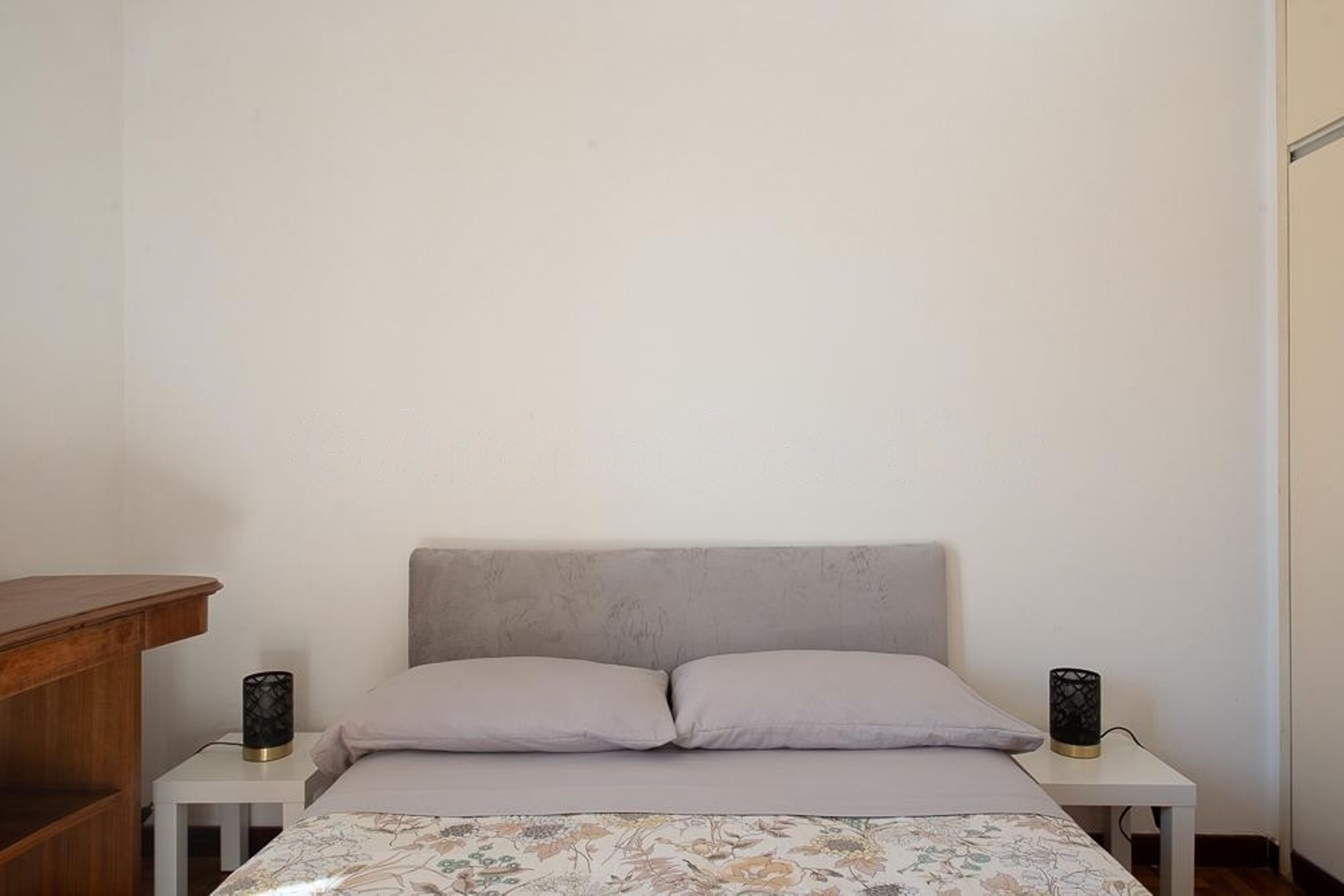 A bedroom with a bed, two bedside tables, and a nightstand.