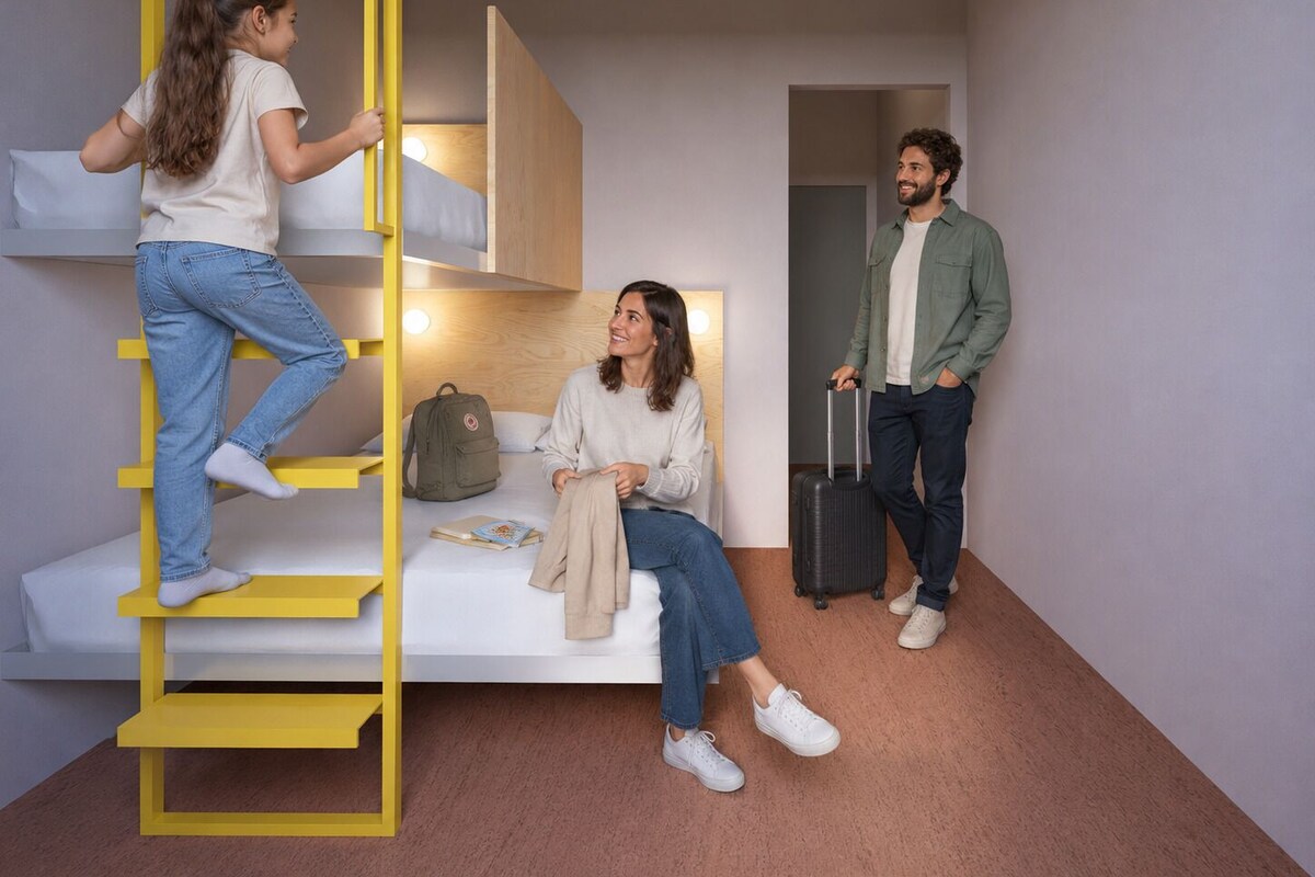 Een kleine kamer met een stapelbed, een bureau en een koffer.