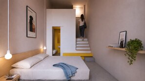 Een slaapkamer met een bed, een bedlampje en een trap naar een badkamer.