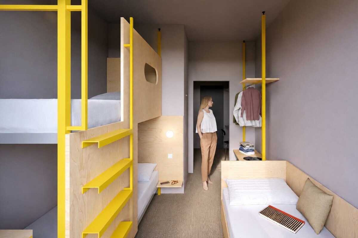 Een kleine hotelkamer met stapelbedden, een bureau en een kledingkast.
