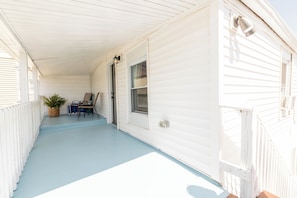 Eine überdachte Veranda mit blauem Boden, einem Topfpflanzen und einem Stuhl.