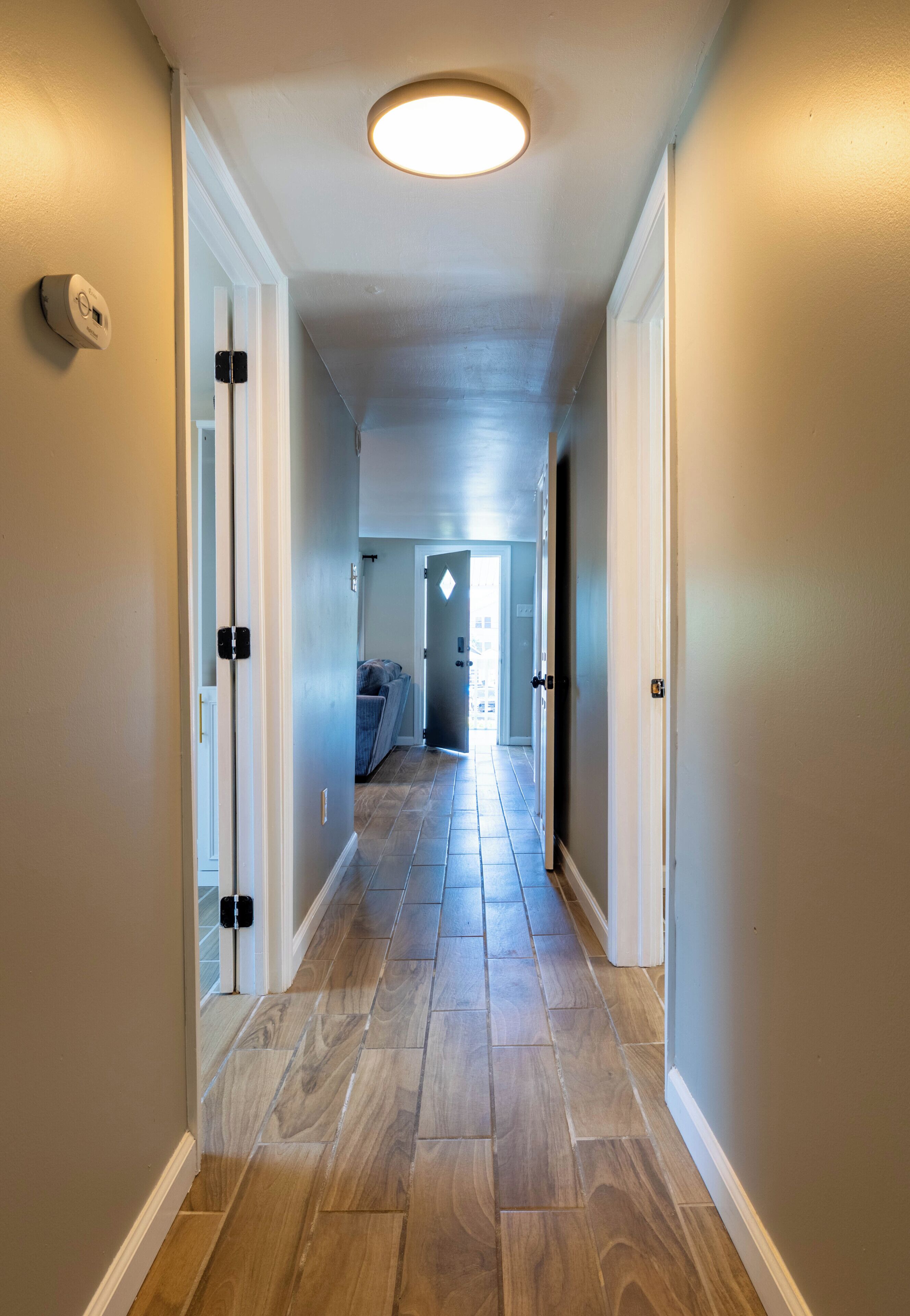 A hallway with a light fixture, a thermostat, and a door leading to a room with a view.